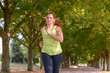 © michaelheim - Fit middle-aged woman jogging through a park
