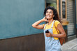 © javiindy - Attractive African woman listening to music with earphones outdoors. Black girl in casual clothes with curly hairstyle in urban background.
