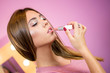 © Bojan - Portrait of teenage girl applying pink lipstick on her lips indoors