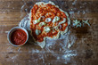 pizza with onion and red tomato sauce over a wood table with flour