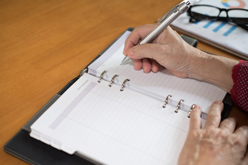 woman hand with pen writing note on notebook at office