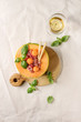 Melon and ham or prosciutto salad served in half of Cantaloupe melon, decorated fresh basil and grissini bread on wooden serving board over white linen cloth with glass of white wine. Flat lay, space
