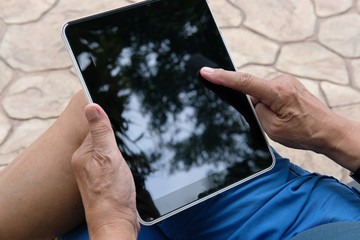 man holding tablet. hand texting message, using app with touchpad outdoor