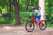 © andrei310 - Cyclist in helmet on an orange bike doing a trick in a springboard jump in the forest, motion blur