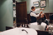 © primipil - Barbershop with wooden interior. Bearded model man and barber.