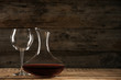 Elegant decanter with red wine and glass on wooden table