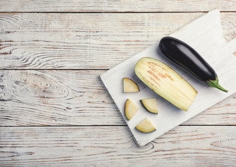 Board with ripe eggplants on wooden background, top view