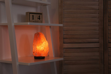 Himalayan salt lamp on shelf in dark room