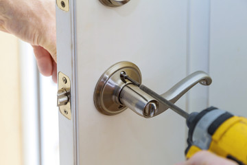 Wall Mural - handyman repair the door lock in worker's hands installing new door locker