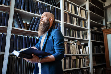 Wall Mural - Stylish bearded man with book in library