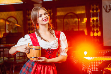 Wall Mural - Young beautiful girl with a wooden mug of beer in hands at a party Oktoberfest.