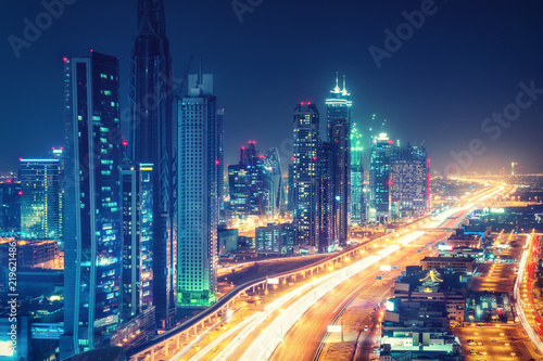Obraz Dibond Sceniczna nocna linia horyzontu w centrum Dubaj, Zjednoczone Emiraty Arabskie. Widok z lotu ptaka na autostrady i drapacze chmur w oddali.