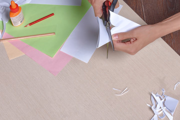 the girl cuts with scissors, colored paper, sitting at the table