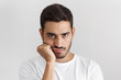 © Damir Khabirov - Close up portrait of bored young man in white tshirt with head on chin isolated on gray background