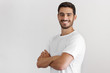 © Damir Khabirov - Indoor daylight portrait of young european caucasian man isolated on gray background, standing in white t-shirt with arms crossed, smiling and looking straight at camera