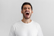 © Damir Khabirov - Screaming with closed eyes crazy young man in blank white t-shirt isolated on gray background