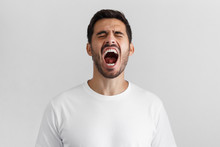 Screaming With Closed Eyes Crazy Young Man In Blank White T-shirt Isolated On Gray Background