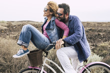 Happy Adult Caucasian, Couple Having Fun With Bicycle In Outdoor Leisure Activity. Concept Of Active Playful People With Bike During Vacation - Everyday Joy Lifestyle Withouth Age Limitation -