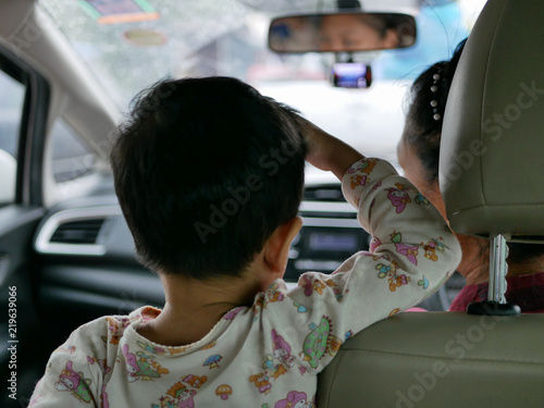 Fotografia, Obraz Asian baby standing on a driving car and refused to sitting and fastening the sa