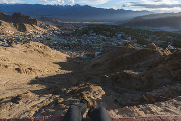 Wall Mural - travelling in leh city, in ladakh, india. a man sitting on cliff enjoying leh city view in the morni