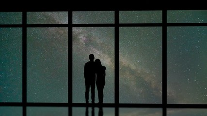 Wall Mural - The man and woman standing near windows on the starry sky background. time lapse