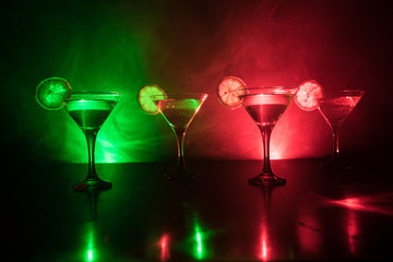 Several glasses of famous cocktail Martini, shot at a bar with dark toned foggy background and disco lights. Club drink concept.