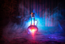 Antique And Vintage Glass Bottles On Dark Foggy Background With Light. Poison Or Magic Liquid Concept.