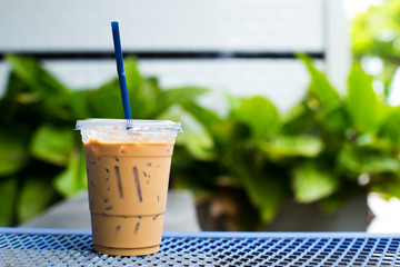 take-home cup with straw of ice coffee on streel  table