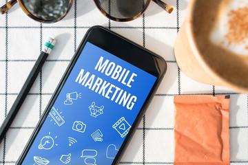 Poster - top view mobile marketing feature on mobile screen with coffee cup,sunglasses,pencil on white table cloth.digital advertising.