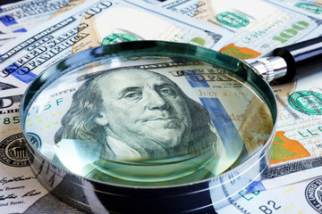 Magnifying glass on dollar banknotes. Finances and exchange.