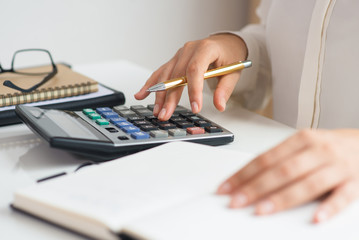 Closeup of accountant calculating profit. Notebook, glasses and calculator lying on desk. Accountancy concept. Cropped view.