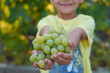 the boy is holding the grapes