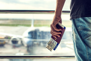 Closeup of man holding passports and boarding pass at airport. Traveling concept