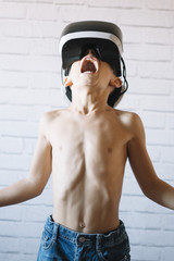 Little happy boy using VR glasses over a white bricks background