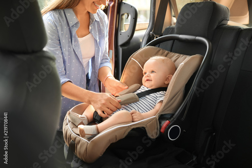 Cuadros en Lienzo Mother fastening baby to child safety seat inside of car