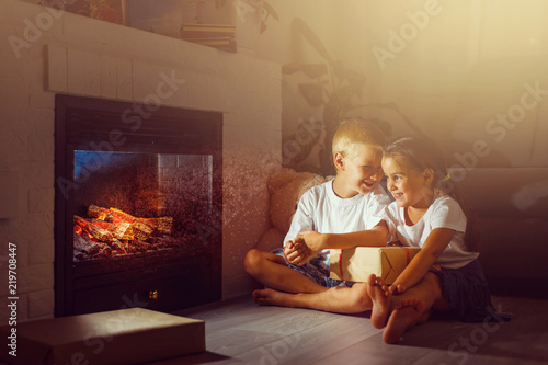 Fotomural happy children with magic gift at home near fireplace