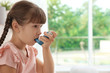© New Africa - Little girl using asthma inhaler on blurred background