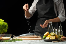 Chef Salting Mackerel Fish On A Black Background