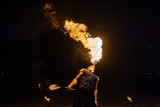 Fototapeta  - Fire show artist breathe fire in the dark