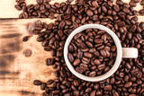 Fototapeta Mapy - Cup of coffee full of coffee beans on wood background