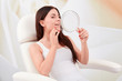 © Artur Nyk - Cosmetic treatments in a professional cosmetic clinic - a young woman looks at her face in the mirror