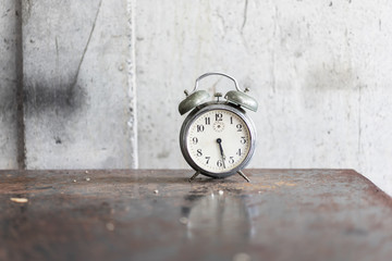 Old alarm clock on the ancient iron table.