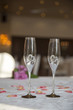 elegantly served with glasses, cutlery and decorated with flowers tables with white tablecloths and burning candles in candlesticks in the blurred background of the fashionable restaurant hall.
