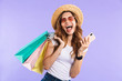 © Drobot Dean - Screaming cute woman isolated over purple wall background holding shopping bags using mobile phone.