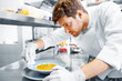 © Syda Productions - food cooking, profession and people concept - happy male chef cook serving and cleaning plate of soup at restaurant kitchen