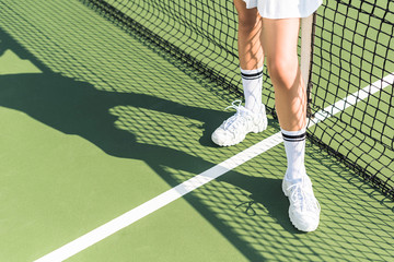 partial view of female tennis player standing near tennis net on court