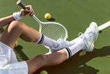 partial view of female tennis player with racket resting on tennis court