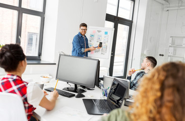 business, technology and people concept - man showing smartphone user interface design to creative team at office presentation