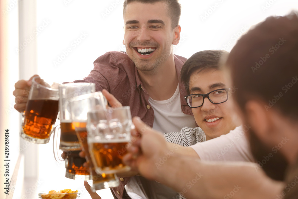 Group of friends clinking glasses with beer in bar