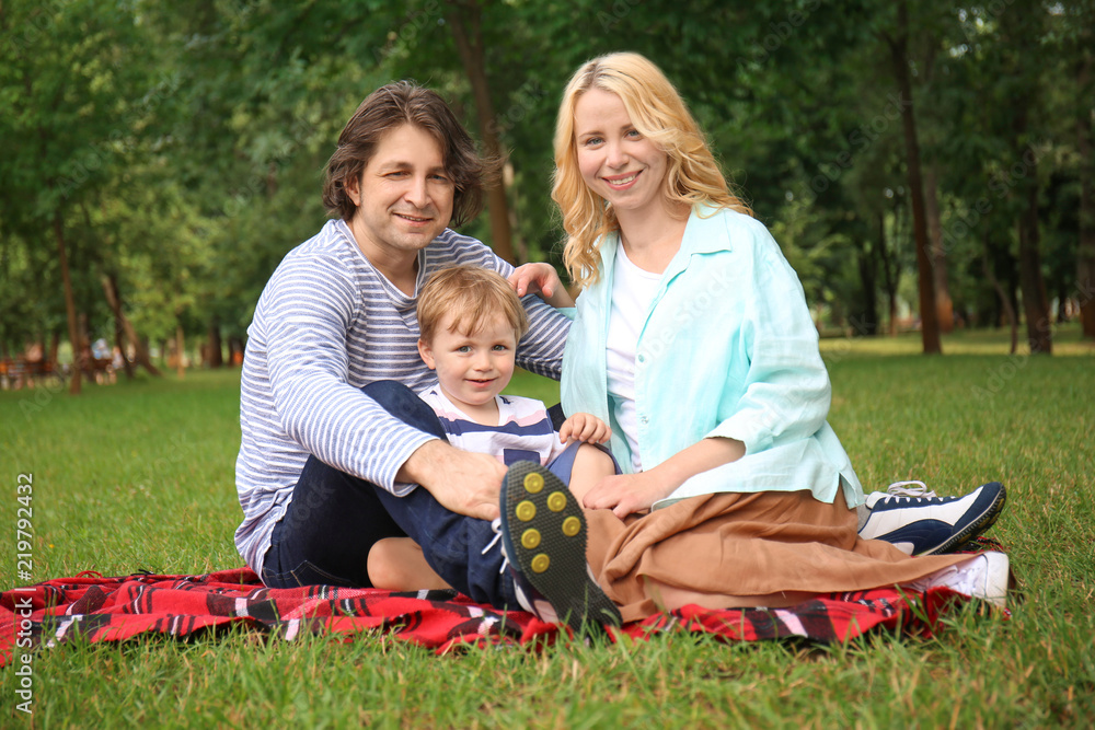 Happy family resting on plaid in park